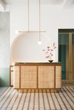 a vase with flowers is sitting on the counter in front of an entrance way that has a circular light fixture above it