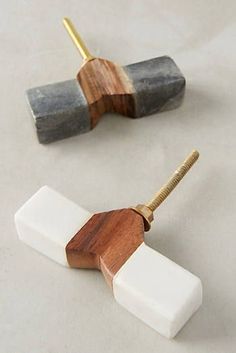 two pieces of wood and white marble are on the table next to each other, with one piece being held by a gold - plated hook