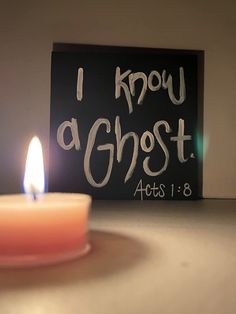 a lit candle sitting on top of a table next to a sign that says i know a ghost