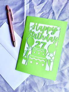 a green birthday card sitting on top of an envelope next to a pen and paper