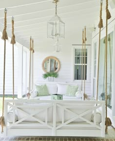 a white porch swing with pillows on it