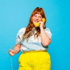 a woman with glasses is talking on the phone and holding an old fashioned telephone to her ear