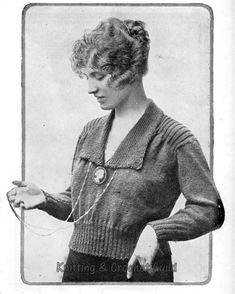 an old black and white photo of a woman holding something in her right hand while wearing a sweater