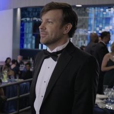 a man in a tuxedo standing at a table