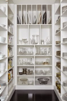 an organized pantry with white shelves filled with dishes