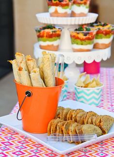 an orange bucket filled with food next to cupcakes and crackers on a table