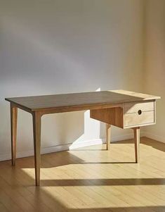 a wooden table sitting on top of a hard wood floor next to a white wall