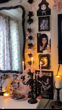 a table topped with candles and pictures on the wall next to a mirror in front of a window