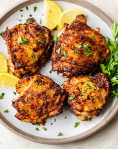 three pieces of chicken on a white plate with green sauce and garnishes