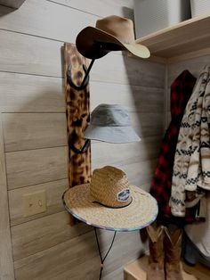 a hat is sitting on top of a table next to a coat rack and boots