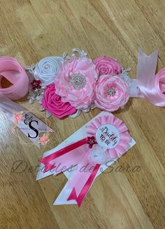 pink and white flowers are sitting on the floor next to ribbons, tags, and other items