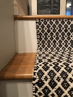 a black and white blanket sitting on top of a stair case next to a wooden banister