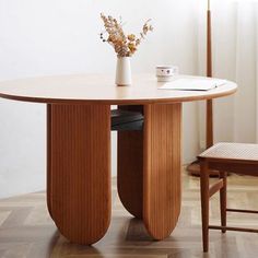 a vase with flowers on top of a wooden table next to a chair and desk