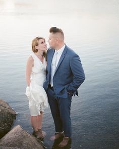 a man and woman standing next to each other near the water