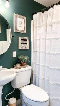 a white toilet sitting under a bathroom mirror next to a sink and bathtub covered in shower curtain