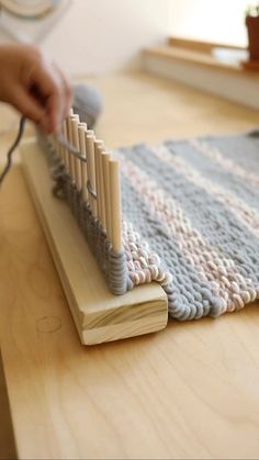 a person is knitting on a wooden table