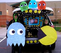 two children in costumes standing next to a car with decorations on the hood and windows