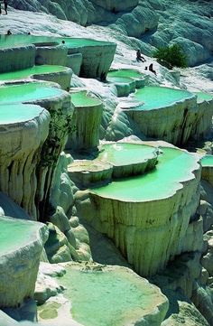 people are standing on the rocks near some green water in an area that looks like it is