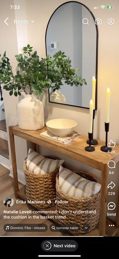 a table with two baskets and a mirror on it next to a plant in a vase