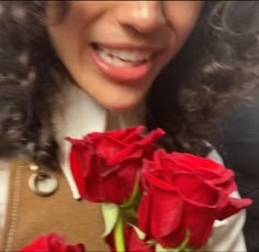 a close up of a woman holding roses in her hand and smiling at the camera