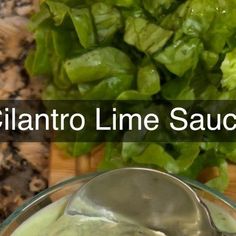 a bowl filled with green sauce next to a pile of lettuce