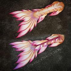 two pink and yellow fish are on the ground with their tails curled up to look like they're swimming