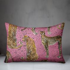 a pink pillow with cheetah and leopards on the front, against a grey background