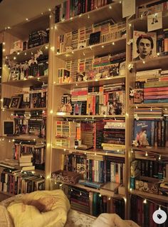 a bookshelf filled with lots of books next to a wall covered in lights