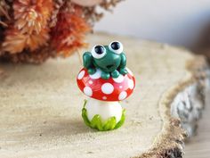 a frog figurine sitting on top of a mushroom