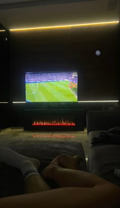 a person laying in front of a television with a soccer game on the tv screen