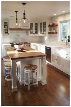 a large kitchen with white cabinets and wooden counter tops, along with two stools at the island