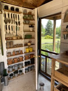 a kitchen with pots and pans hanging on the wall next to an open door