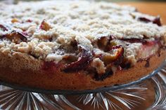 a close up of a cake on a glass platter with crumbs and toppings