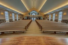 an empty church with rows of pews in front of large windows and wood flooring