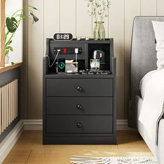 an alarm clock sits on top of a nightstand next to a bed