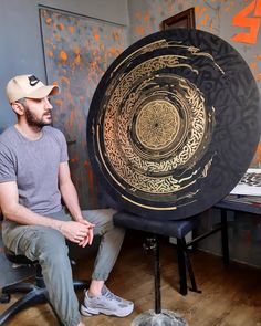 a man sitting on a chair next to a large black and gold plate in front of him