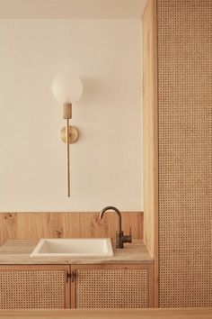 a bathroom sink sitting under a mirror next to a wall mounted faucet and wooden cabinets