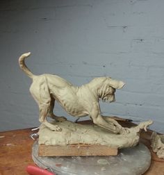 a statue of a dog on top of a piece of wood next to a pencil