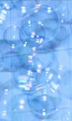 soap bubbles floating in the air on a tiled floor with blue and white tiles behind them