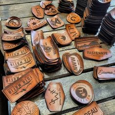 many leather badges are laid out on a wooden table and placed next to each other