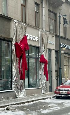 a red car parked in front of a building with silver foil wrapped around the windows