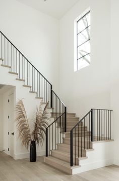 there is a plant in the vase on the floor next to the stair railings