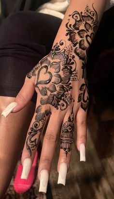 a woman's hand with black and white henna tattoos on her left arm