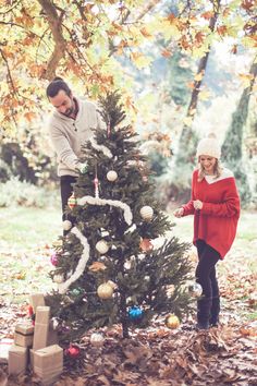 a man and woman decorating a christmas tree