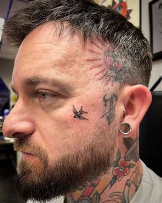 a man with a tattoo on his neck and behind his ear is looking at the camera