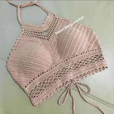 a crocheted top is laying on the bed with its laces pulled back