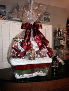 a gift basket is wrapped in plastic and tied with red ribbon, sitting on a counter