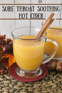 two mugs filled with orange juice and cinnamon on top of a woven place mat