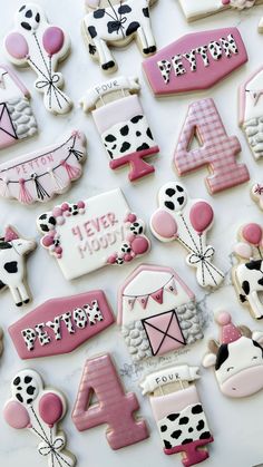 decorated cookies with numbers and farm animals are displayed on a white tablecloth for a birthday party