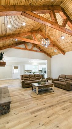 a living room filled with furniture and a wooden beamed ceiling above it's hardwood flooring